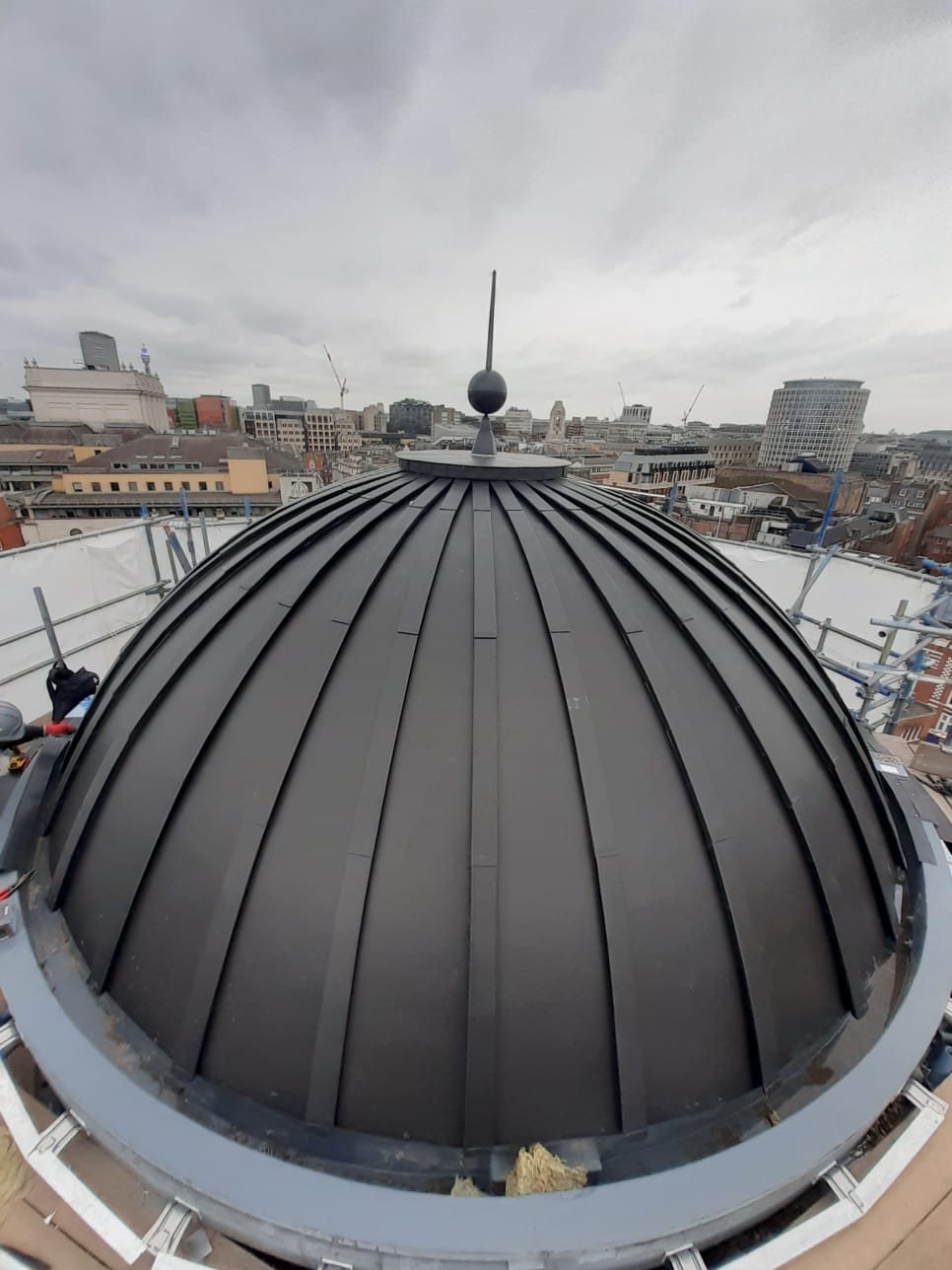 Anthracite standing seam zinc dome with a cast finial above the London rooftops