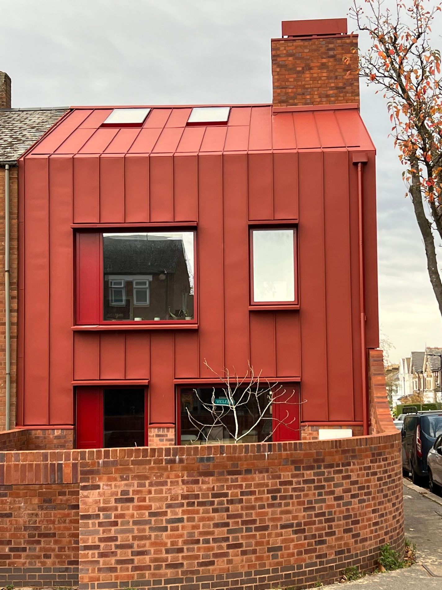 Red standing seam townhouse. Full three storey red standing seam envelope over new brickwork
